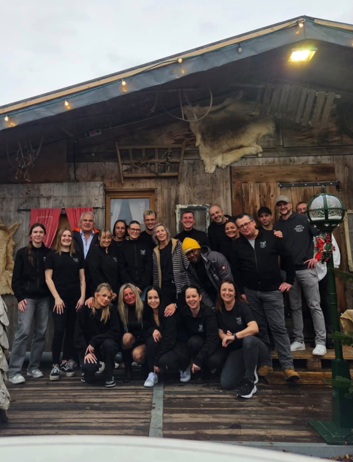 Das Team des Skandidorfs gemeinsam vor einer der Holzhütten